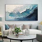 A crashing blue wave with broad white foam above a cream sofa